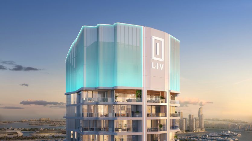 A modern high-rise building with a bright blue outline on its rounded facade, prominently displaying the "liv" logo, against an early evening sky with a view of Dubai's waterfront.