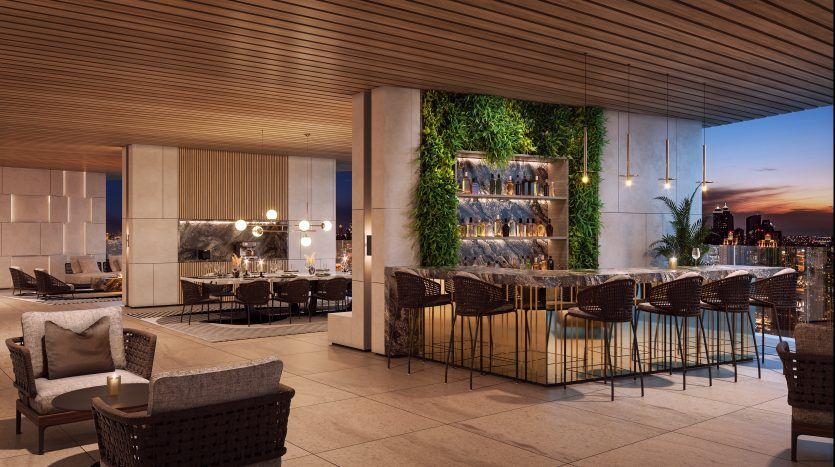 A luxurious rooftop dining room at dusk with elegant furnishings, mood lighting and a wall of greenery. Presented by a leading Dubai real estate agency, the backdrop features a city skyline beneath
