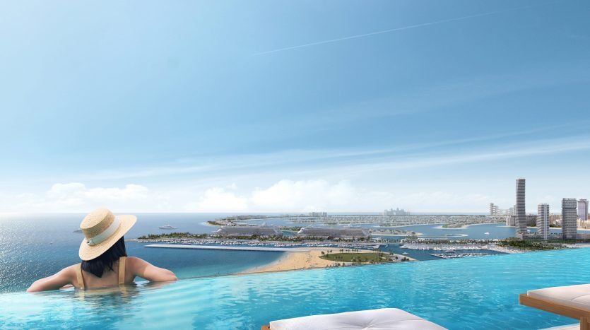 A woman wearing a sun hat relaxes by an infinity pool overlooking a panoramic view of the rooftops of a coastal city from her villa in Dubai under a clear blue sky.