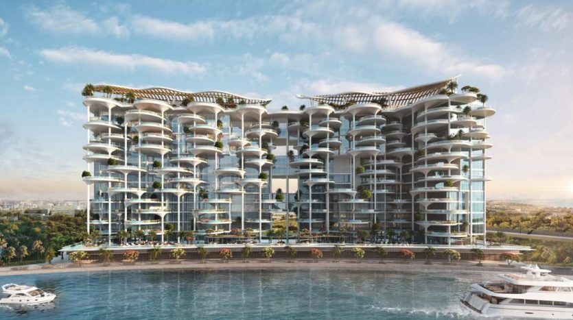 A modern, luxury apartment building on Dubai's waterfront with several balconies, vast glass facades and topped with green roofs. Several yachts are moored nearby in a clear-blue stretch of water.