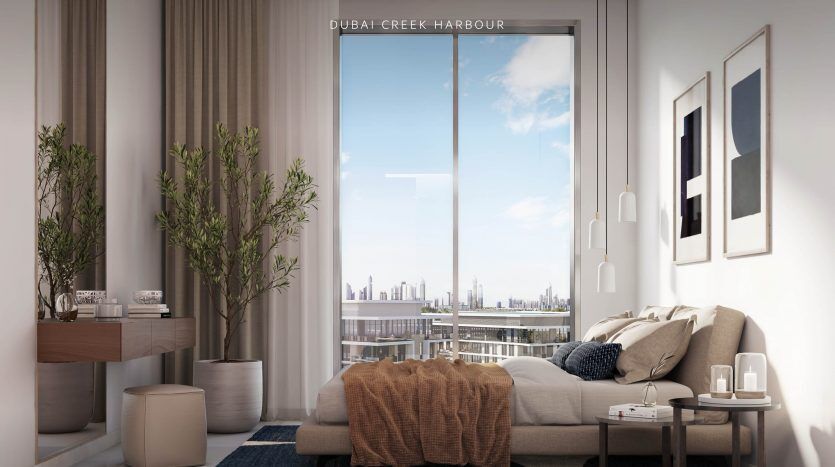 Une chambre moderne dans une villa surplombant les toits de la ville. La chambre comprend un lit avec un tapis bleu, des murs blancs, des œuvres d'art encadrées et des plantes d'intérieur. Le texte sur l'image indique « The Cove Dubai Creek