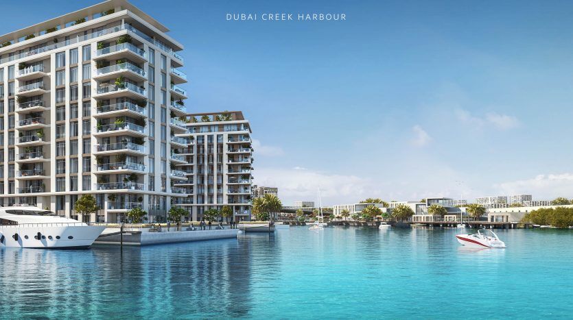 Image promotionnelle de « The Cove » au port de Dubai Creek, représentant des bâtiments résidentiels modernes en bord de mer, comprenant des villas et des appartements. La scène comprend un ciel bleu clair, une eau calme avec des bateaux et un aménagement paysager vibrant.