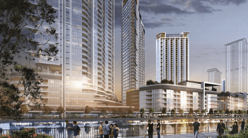 A night scene of a modern urban river in Dubai with illuminated high-rise buildings. People walk and chat along the flowery promenade.