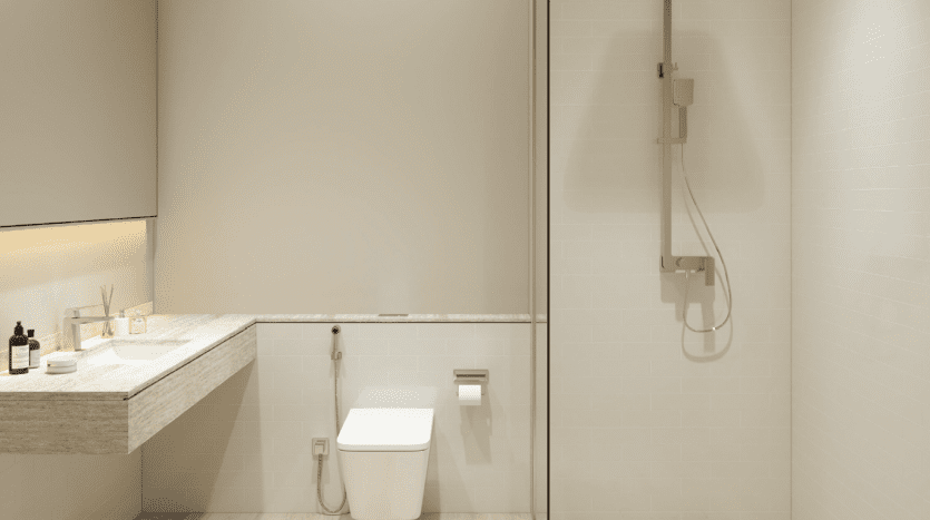 A modern bathroom in a Dubai villa with a beige color palette featuring a glass shower, wall-mounted toilet and basin with marble countertop and recessed lighting.