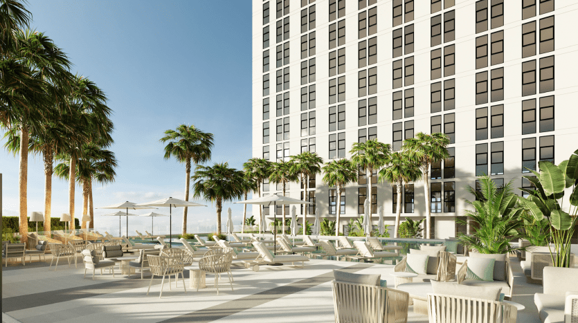 Luxury outdoor patio in a Dubai apartment with comfortable seating, umbrellas and surrounded by tall palm trees under a clear, sunny sky.