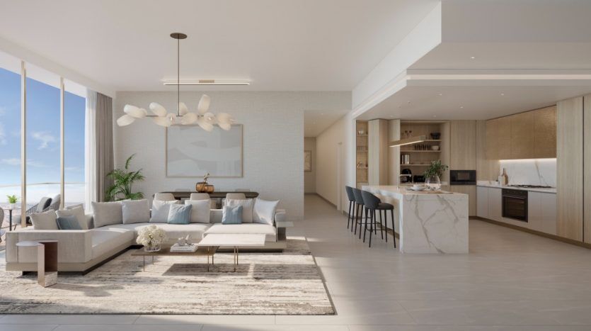 Salon et cuisine décloisonnés modernes avec vue sur la plage dans un appartement de Dubaï. Les caractéristiques comprennent un grand canapé sectionnel, une décoration minimaliste et un îlot de cuisine avec des tabourets de bar. Une lumière naturelle vive remplit l'espace