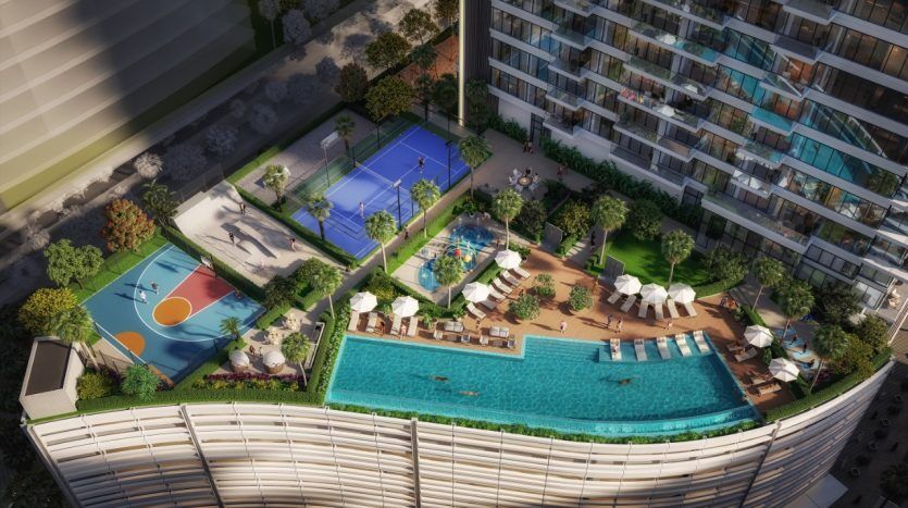 Vue aérienne d'un toit d'hôtel luxueux avec piscine, chaises longues, terrain de basket et court de tennis, entouré d'une verdure luxuriante et d'appartements modernes à Dubaï.