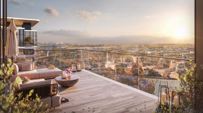Un balcon doté d'un mobilier moderne surplombe un vaste paysage urbain de Dubaï, baigné de lumière chaude et présentant un ciel clair et des immeubles de grande hauteur au loin.