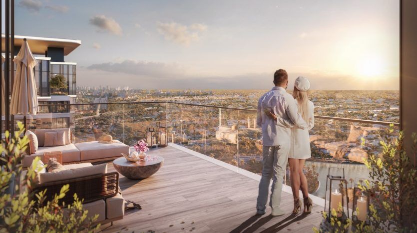 Un couple se tient sur un luxueux balcon au coucher du soleil, surplombant un vaste paysage urbain depuis leur appartement à Dubaï, entouré d'un mobilier d'extérieur confortable et d'éléments décoratifs.