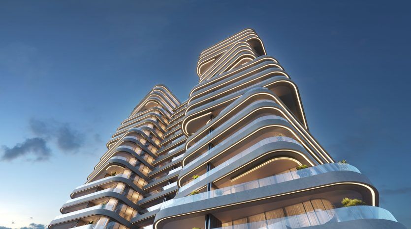 Des bâtiments architecturaux modernes à plusieurs étages avec des balcons fluides et incurvés sur un ciel bleu avec des nuages clairs, mettant en valeur le design futuriste et servant de principales opportunités d'investissement à Dubaï.