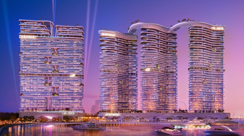 Une ligne d'horizon futuriste au bord de l'eau comprenant quatre immeubles de grande hauteur aux courbes uniques, illuminés par un ciel crépusculaire, avec des bateaux amarrés au premier plan à Dubaï.