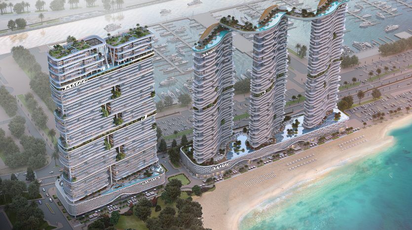 Vue aérienne de trois immeubles d'appartements futuristes de grande hauteur à Dubaï avec des jardins luxuriants sur les toits, situés à côté d'une plage aux eaux turquoise, entourés d'un parking et d'une verdure luxuriante.