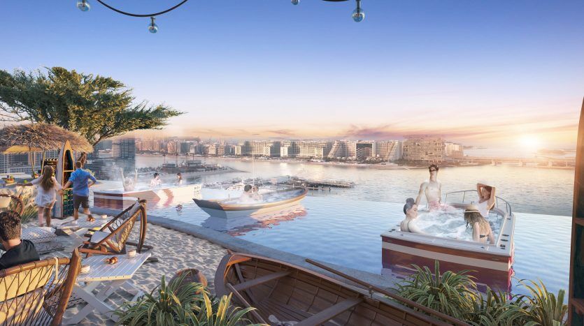 Les gens profitent d’un coucher de soleil dans une luxueuse villa en bord de mer à Dubaï avec une piscine à débordement surplombant une marina pittoresque avec des bateaux. Certains sont dans un bain à remous, d'autres discutent au bord de la piscine, dans une ambiance animée.