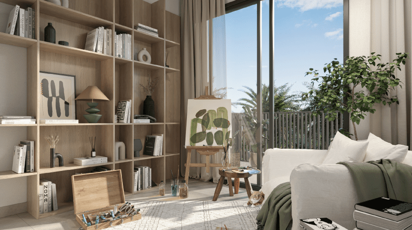 Un studio d'art confortable et ensoleillé dans un appartement à Dubaï, comprenant une grande étagère, un chevalet avec un tableau, des fournitures d'art et un canapé moelleux près d'une fenêtre avec vue sur