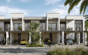 Complexe de villas modernes aux lignes épurées et aux couleurs neutres, avec résidents et véhicules à l'extérieur, entourés d'une verdure luxuriante et de palmiers sous un ciel dégagé.