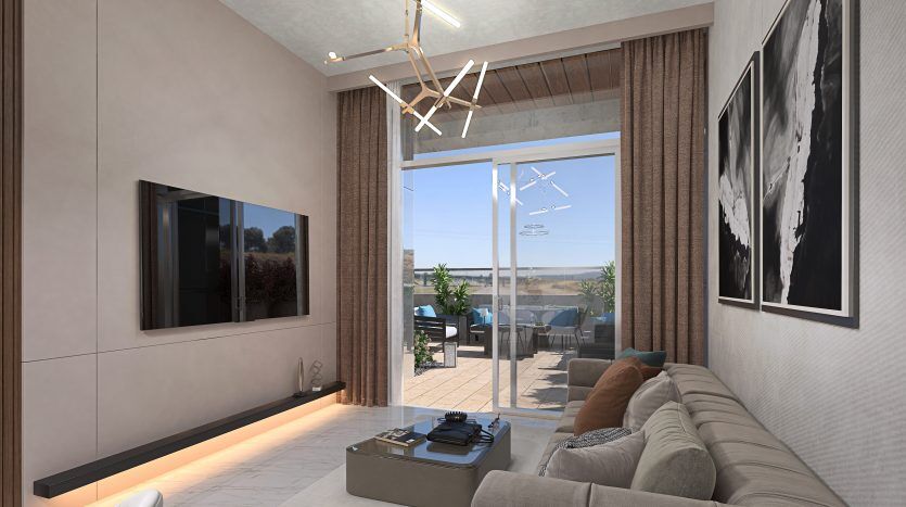 Un salon moderne dans un appartement de Dubaï avec un canapé beige, une télévision murale, des œuvres d'art abstraites et de grandes fenêtres menant à une terrasse avec coin salon extérieur.