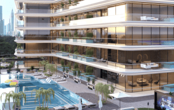 Un immeuble luxueux de grande hauteur avec des balcons en terrasse donnant sur une piscine avec des chaises longues et des cabanes, sur fond de gratte-ciel de la ville au crépuscule à Dubaï.
