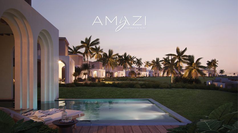 Façade luxueuse du complexe au crépuscule, avec une piscine au premier plan et des arcades élégamment éclairées menant à des jardins luxuriants, avec le logo « Amazing Immobilier Dubai » en haut au centre.