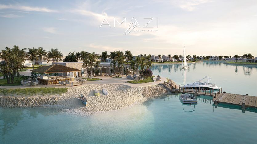 Une station balnéaire luxueuse avec le nom « amazi » affiché en haut. La vue comprend un lagon calme, des villas aux toits de chaume, des plages de sable blanc et un quai avec un
