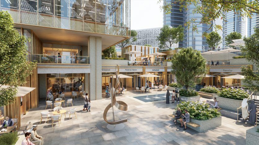 Un centre commercial extérieur animé à Dubaï avec une architecture moderne comprenant plusieurs niveaux, des terrasses bordées de boutiques et de cafés, des gens qui se mélangent et une sculpture artistique près d'une petite piscine.