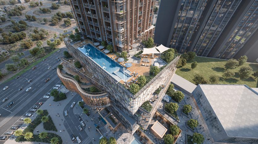 Vue aérienne d'un complexe architectural moderne à Dubaï comprenant un bâtiment avec une piscine sur le toit, des espaces paysagers et des routes environnantes.