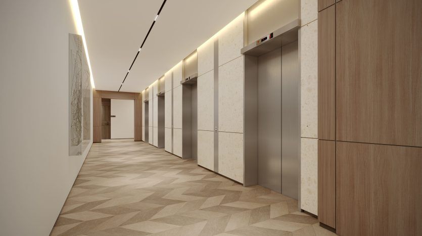 Intérieur moderne d'un couloir d'immeuble à Dubaï comprenant deux portes d'ascenseur, des murs lambrissés, des sections en marbre élégantes et un sol à motifs géométriques. Un éclairage décoratif illumine le couloir.