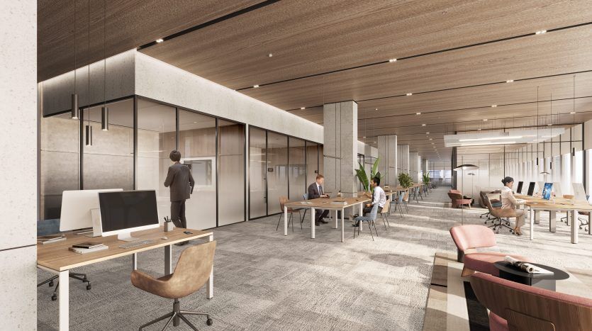 Espace de bureau moderne doté d'un plan d'étage ouvert avec des bureaux, des ordinateurs et des employés qui travaillent. Il y a un mélange de tables communes et de stands privés, avec de la lumière naturelle inondant de grandes fenêtres, idéal pour l'investissement.