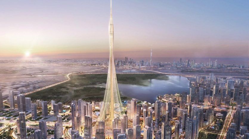 Vue aérienne d'une ville futuriste au coucher du soleil avec un gratte-ciel imposant et élancé au centre, entouré de nombreux immeubles de grande hauteur, dont plusieurs propriétés de l'immobilier Dubaï et un grand plan d'eau.