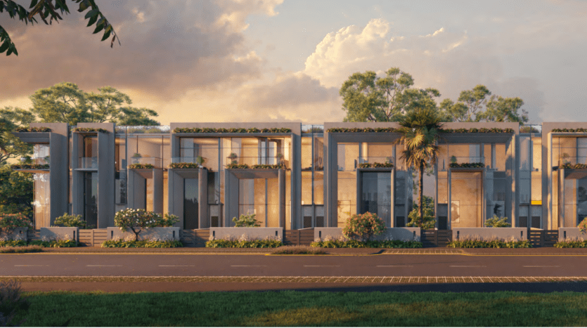 Row of modern townhouses with large windows and lush rooftop gardens at sunset, against a backdrop of cloudy skies in Dubai, seen from across a palm-lined street.