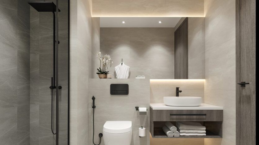 Intérieur de salle de bains moderne comprenant une douche à l'italienne, un lavabo mural, des armoires, des carreaux gris élégants et un éclairage doux. La décoration comprend des serviettes et une petite plante en pot, idéale pour une villa en