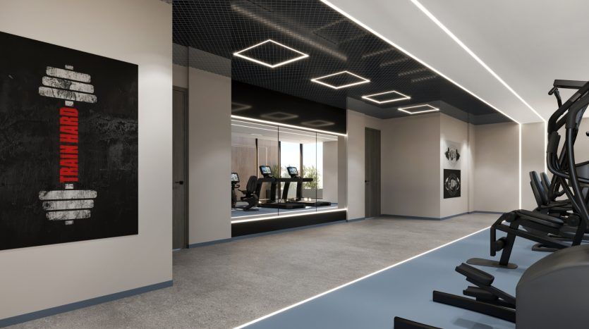 Intérieur de salle de sport moderne au design élégant avec éclairage LED au plafond, affiche de motivation « Entraînez-vous dur » au mur et divers équipements d'exercice, notamment des tapis roulants et des poids, disponibles dans le cadre d'une opportunité d'investissement.