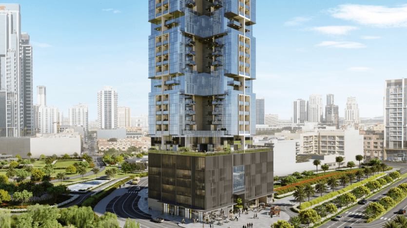 Un immeuble moderne de grande hauteur doté de vastes façades vitrées et de balcons verts se dresse en bonne place dans un cadre urbain, entouré de parcs luxuriants et d'autres gratte-ciel sous un ciel dégagé à Dubaï.