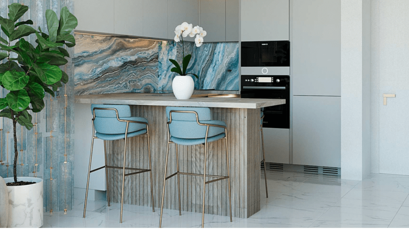 Cuisine moderne avec un îlot en marbre présentant un motif bleu et marron unique, deux tabourets hauts bleus élégants et des plantes vertes luxuriantes ajoutant une touche de nature dans une villa de Dubaï.