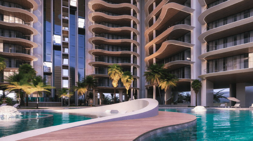 Immeuble d'appartements moderne avec balcons ondulés donnant sur une piscine entourée de palmiers au crépuscule à Dubaï.