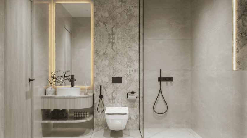 Salle de bains moderne avec murs en marbre, située dans un appartement de premier ordre à Dubaï, comprenant une douche vitrée, des toilettes murales et une vasque avec lavabo, miroir sous-éclairé et serviettes bien organisées.