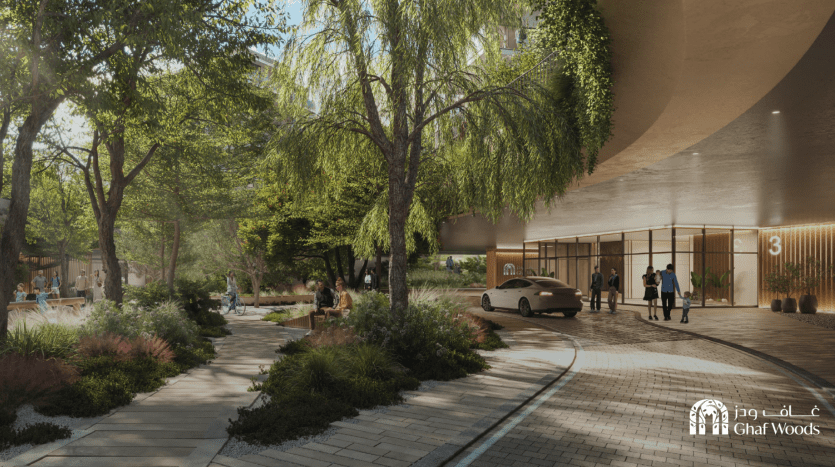 Une cour urbaine sereine à Ghaf Woods abrite une verdure luxuriante, une allée pavée sinueuse et des bâtiments modernes. Les gens se promènent ou se détendent sur des bancs, tandis qu'une voiture est garée près de l'entrée du bâtiment, créant une atmosphère communautaire tranquille.