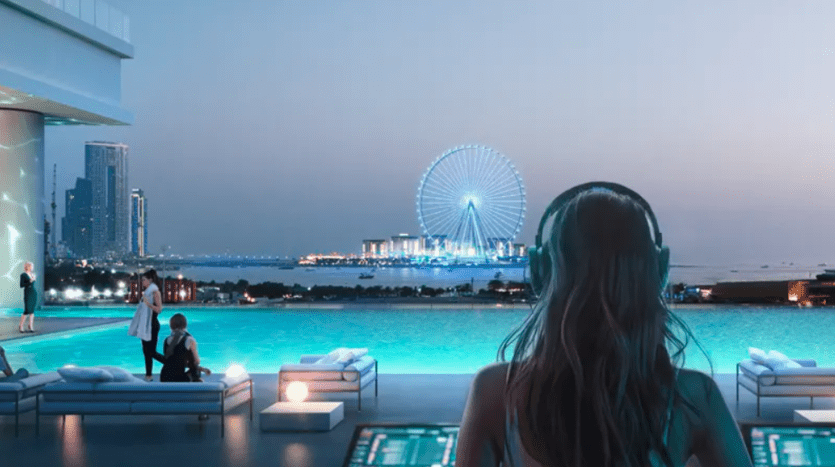 A person wearing headphones overlooks an infinity pool at dusk, with skyscrapers and an illuminated Ferris wheel in the background. Others are around the pool, enjoying the serene ambience and modern outdoor relaxation area.