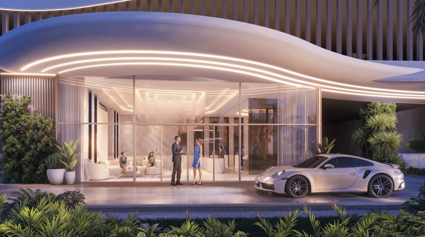 A modern, luxurious lobby with glass walls and a flowing curved roof featuring LED lights welcomes guests to The Pier. An elegant sports car is parked out front, and two people converse near the entrance. Inside, several people sit on plush chairs, amid elegant decor and lush greenery outside.