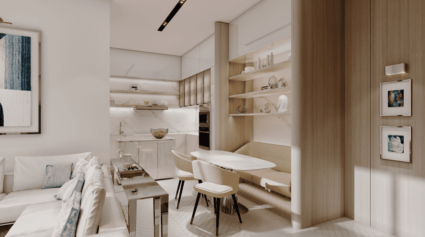 A modern kitchen and dining area with light woodwork and white cabinetry at the Pier. The dining area features a built-in bench and three chairs around a white table. Above, open shelves display decorative objects. The adjacent living room features a light-colored sofa.