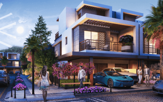 Au crépuscule, un quartier moderne comprend des maisons à deux étages avec balcon. Une voiture de sport bleue et une berline argentée sont garées dans la rue. Les gens marchent et se tiennent près d’arbustes et d’arbres en fleurs sous le ciel nocturne avec une pleine lune projetant une teinte violette sur le paysage.