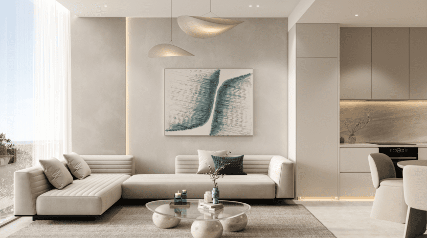 Un salon moderne au design minimaliste présente des canapés beiges REEF 1000, une table basse ronde en verre, des œuvres d'art murales abstraites et d'élégantes suspensions. De grandes fenêtres offrent une lumière naturelle et l'agencement ouvert se transforme en douceur en une cuisine élégante.