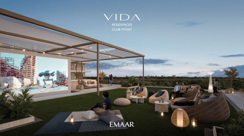 At Vida Residences, enjoy an open-air rooftop cinema at dusk, with comfortable seating and a large screen showing a lively scene. Strings of lights twinkle overhead as people relax in a serene atmosphere, savoring the picturesque landscape in the background.
