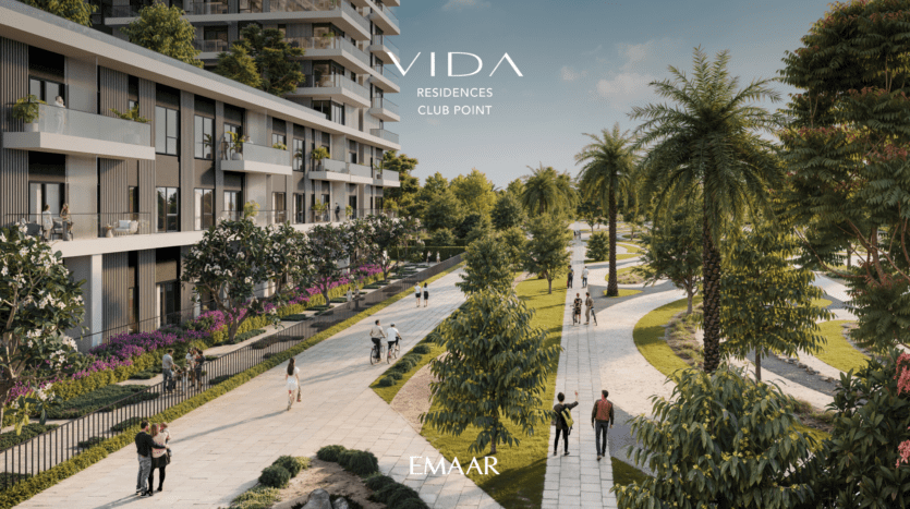 A modern residential building, Vida Residences at Club Point, has a large driveway lined with palm trees and greenery. People stroll along the path under a clear sky. The image features the text: "Vida Residences Club Point" and "Emaar.