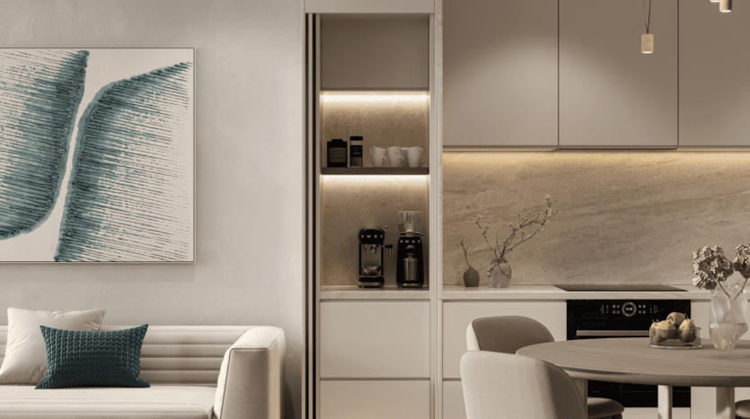 Cuisine et salon contemporains avec canapé beige avec coussin bleu sarcelle, œuvres d'art murales abstraites et REEF 1000, le dernier cri en matière d'équipements de cuisine modernes, ainsi qu'une cafetière et des tasses sur une étagère. Un éclairage minimaliste met en valeur le design neutre et élégant.