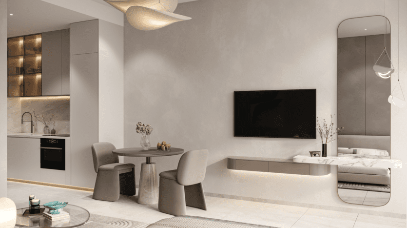 Un espace de vie moderne et minimaliste avec une petite table à manger ronde et deux chaises, équipé du système audio REEF 1000. Une télévision murale est adjacente à un grand miroir. Les armoires épurées de la cuisine et l'éclairage doux aux tons neutres créent une atmosphère calme et sophistiquée.