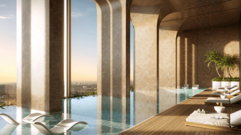 Une élégante piscine intérieure à débordement avec chaises longues offre une vue panoramique sur la ville au coucher du soleil le long de la promenade. De hautes arches et des plantes en pot créent une atmosphère sereine sur la terrasse en bois.
