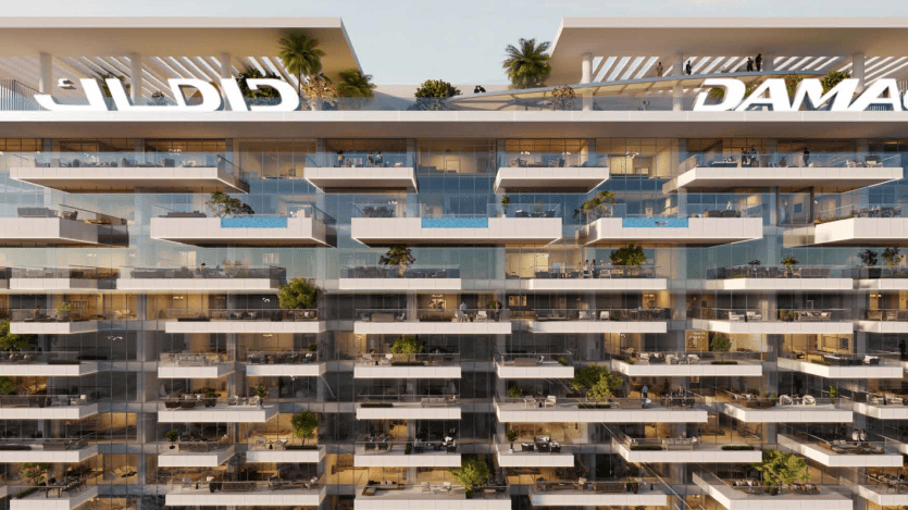 Un immeuble moderne à plusieurs étages près de l'emblématique porte Safa, doté de nombreux balcons en verre avec de petites piscines et de verdure. Le toit comprend des terrasses avec des plantes et des espaces de détente. Cette propriété de Damac présente un design élégant et contemporain.
