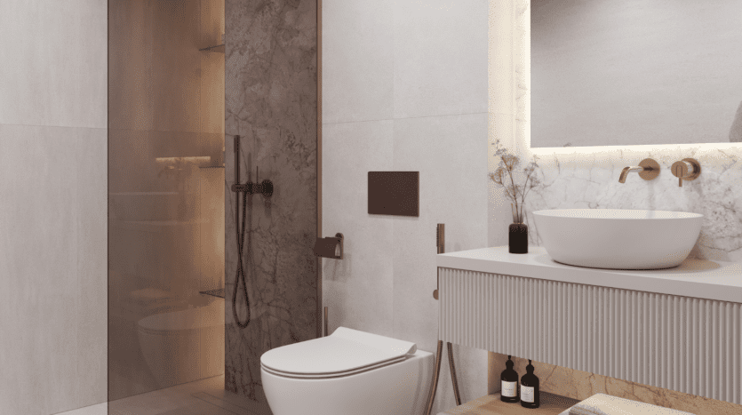 Salle de bains moderne avec toilettes murales, lavabo rond sur meuble blanc, décor minimaliste, étagères encastrées et douche vitrée aux finitions beige et marbre. L'éclairage chaleureux met en valeur le design épuré et élégant.