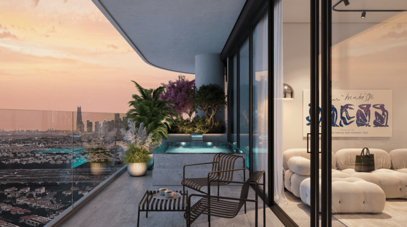 Un balcon moderne avec des balustrades en verre, des plantes en pot et une petite piscine surplombe la ville au coucher du soleil. Deux chaises noires et une table se trouvent à proximité d'un salon intérieur confortable avec des sièges en peluche et des œuvres d'art contemporaines.