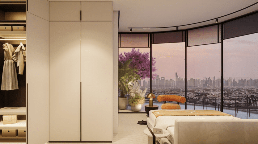 Chambre à coucher moderne avec armoire encastrée, placard ouvert et lit bien fait. De grandes fenêtres allant du sol au plafond révèlent la ligne d'horizon de la ville au coucher du soleil, un arbre à fleurs violettes et des plantes en pot sur le balcon. Décoration minimaliste dans l'ensemble de l'appartement.
